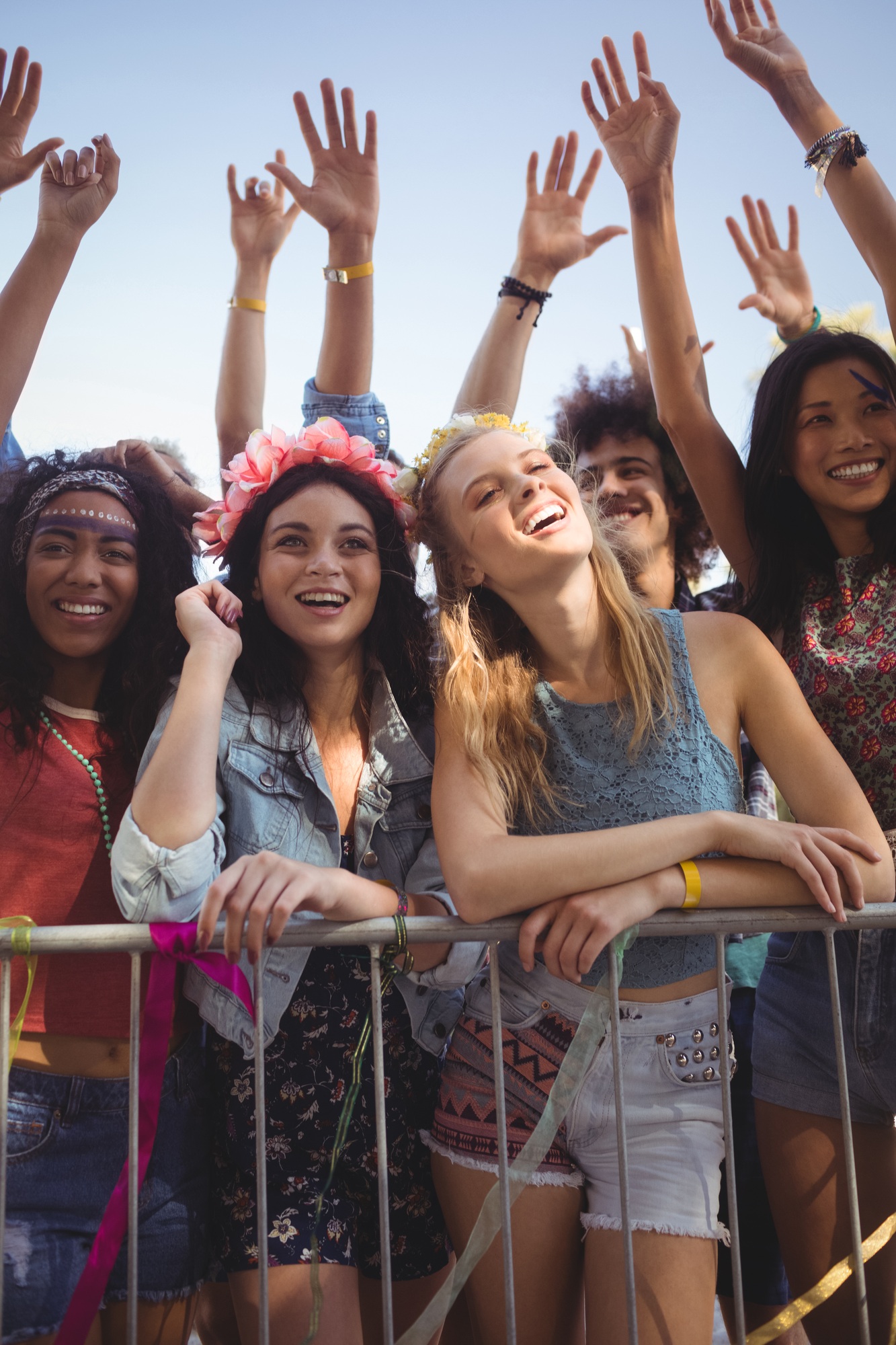 Happy female friends standing by railing at music festival