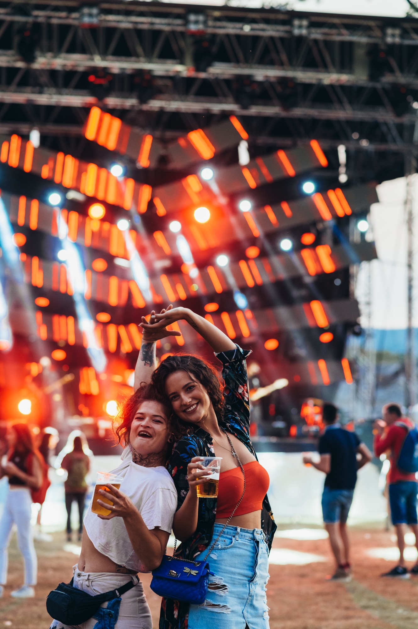 Two beautiful friends drinking beer and having fun on a music festival